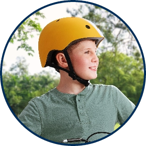 Right-facing profile of young boy with yellow helmet against park background